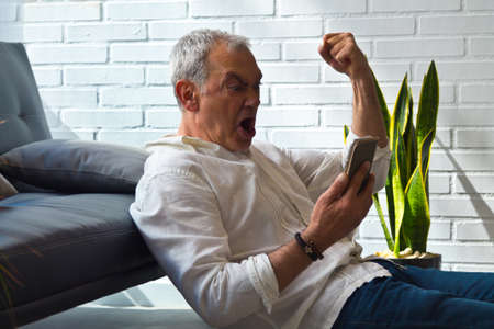 surprised man reading a book on the armchairの写真素材