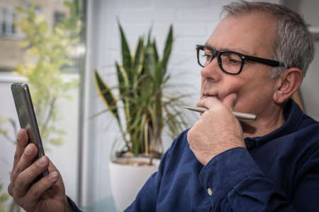 adult man chatting with mobile phone at homeの写真素材