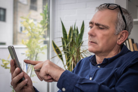 adult man chatting with mobile phone at homeの写真素材