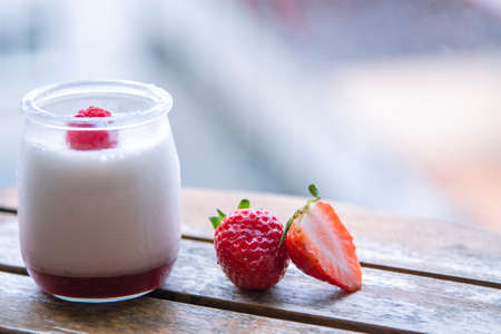 Two strawberry yogurt milk shakes with fresh strawberries on a table next to ingredientsの写真素材