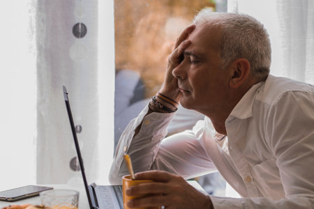 man having breakfast and depressive or bored in front of the laptopの写真素材