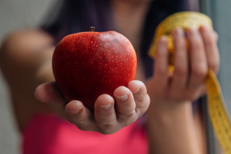 hand with tape measure and apple, concept of diet and health