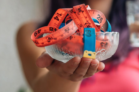 woman holding bowl with colored measuring tapes, concept of diet and health