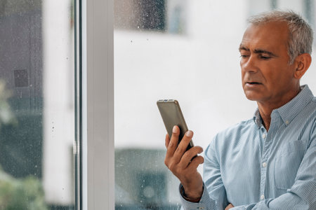 adult man with phone at windowの写真素材