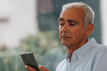 adult man with phone at windowの写真素材