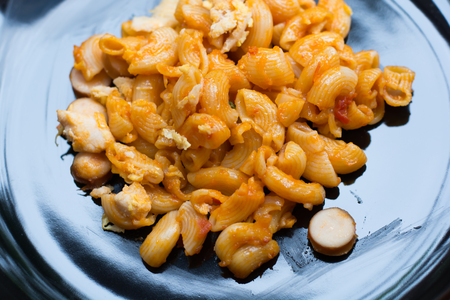 macaroni pasta in tomato sauce on black discの写真素材