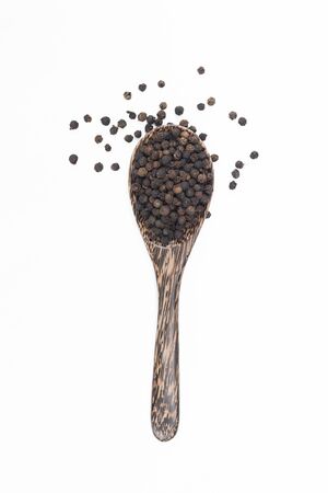 Black pepper in spoon wooden bowl isolated on white backgroundの写真素材