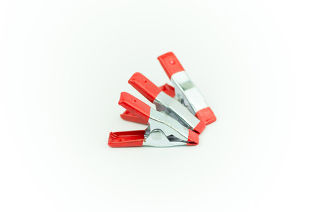 Metal spring clamp with red plastic isolated on whiteの写真素材