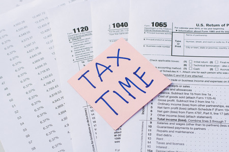 Tax Time written on pink sticker note with on U.S. tax form