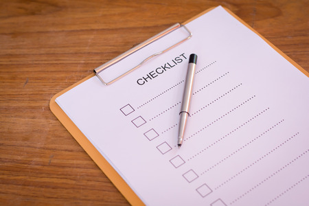 Checklist concept - checklist, paper and a pen with checklist word on wooden tableの写真素材