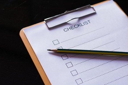 Checklist concept - checklist, paper and a pen with checklist word on wooden table