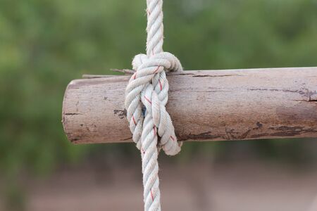 A rope is tied in a knot around a fence post , rope tied knot wood poleの写真素材