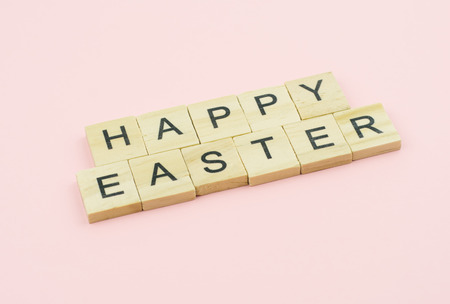 Text wooden blocks spelling the word happy easter on pink backgroundの写真素材