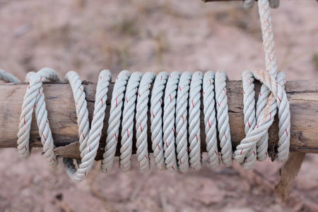 A rope is tied in a knot around a fence post , rope tied knot wood poleの写真素材