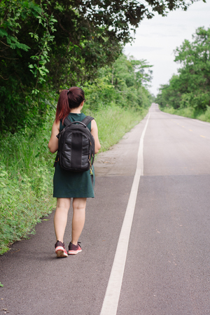 Happy Asian girl backpack in the road and forest background, Relax time on holiday concept travelの写真素材