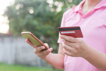 woman hands holding credit card and using cell, smart phone for online shoppingの写真素材
