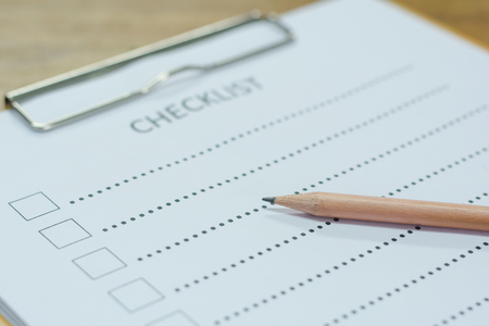 Checklist concept - checklist, paper and a pen with checklist word on wooden tableの写真素材