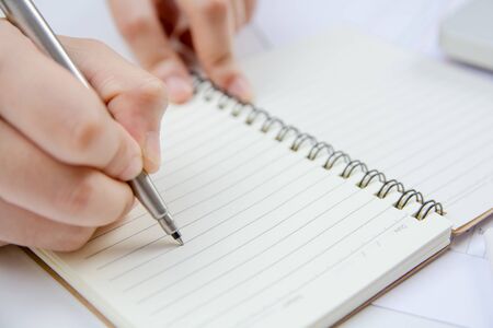 Female hand holding silver pen closeup. doing homework.writing make note