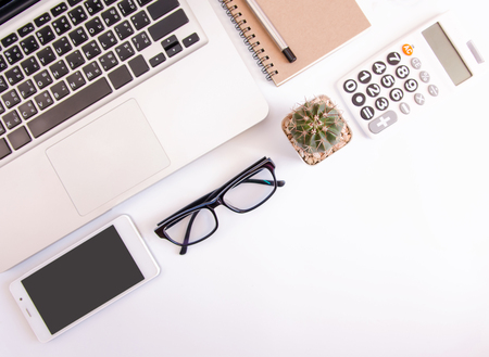 White office desk table, workspace office with laptop, smartphone black screen,pen,calculator, glasses, Top view with copy spaceの写真素材