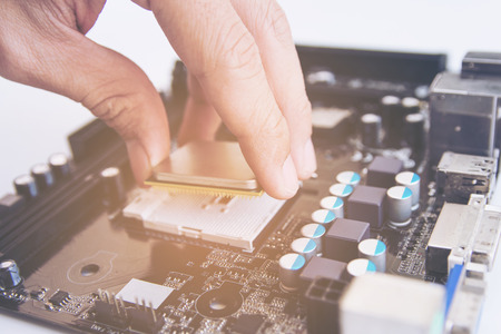 Technician installing CPU chip microprocessor to socket on motherboard 