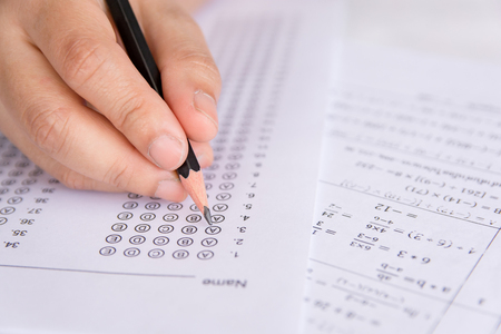 Students hand holding pencil writing selected choice on answer sheets and Mathematics question sheets. students testing doing examination. school examの写真素材