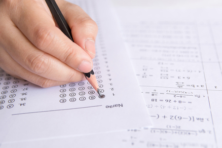 Students hand holding pencil writing selected choice on answer sheets and Mathematics question sheets. students testing doing examination. school examの写真素材