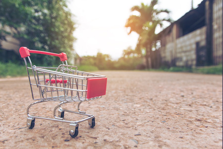 Shopping concept : Small blue shopping cart toy on concrete floor. online shopping consumers can shop from home and delivery service. with copy spaceの写真素材