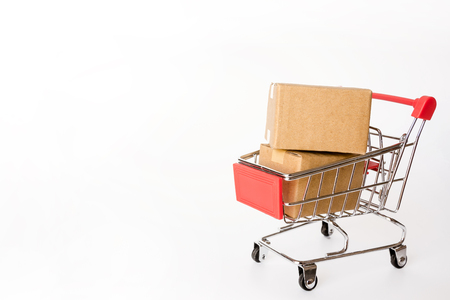 Shopping concept : Cartons or Paper boxes in red shopping cart on white background. online shopping consumers can shop from home and delivery service. with copy spaceの写真素材