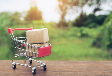 Shopping concept : Cartons or Paper boxes in shopping cart on brown wood table. online shopping consumers can shop from home and delivery service. with copy spaceの写真素材