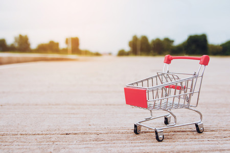 Shopping concept : Small red shopping cart toy on concrete floor. online shopping consumers can shop from home and delivery service. with copy spaceの写真素材