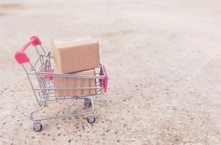 Shopping concept : Cartons or Paper boxes in shopping cart on concrete floor. online shopping consumers can shop from home and delivery service. with copy spaceの写真素材