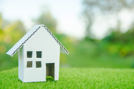 Eco house concept : Cardboard cut house on green grass with copy spaceの写真素材