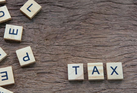 Tax with wooden alphabet blocks, on plank wooden background with copy spaceの写真素材