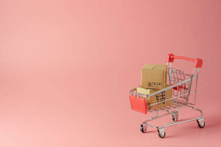 Shopping concept : Cartons or Paper boxes in red shopping cart on pink background. online shopping...