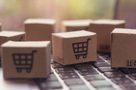 Online shopping - Paper cartons or parcel with a shopping cart  on a laptop keyboard. Shopping service on The online web and offers home delivery.の写真素材