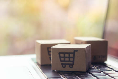 Online shopping - Paper cartons or parcel with a shopping cart  on a laptop keyboard. Shopping service on The online web and offers home delivery.の写真素材