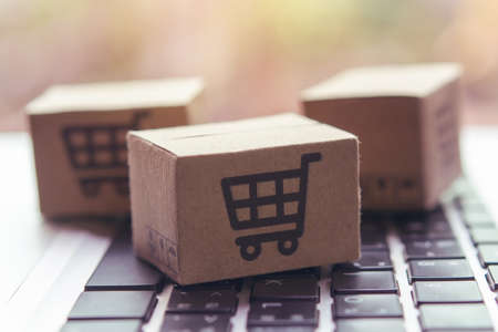 Online shopping - Paper cartons or parcel with a shopping cart  on a laptop keyboard. Shopping service on The online web and offers home delivery.の写真素材