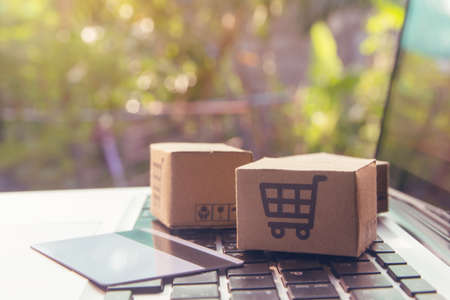 Online shopping - Paper cartons or parcel with a shopping cart   and credit card on a laptop keyboard. Shopping service on The online web and offers home delivery.の写真素材