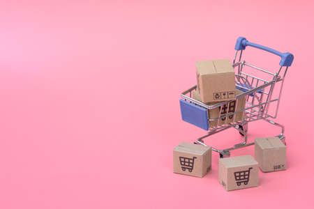 Shopping concept : Cartons or Paper boxes in blue shopping cart on pink background. online shopping consumers can shop from home and delivery service. with copy spaceの写真素材