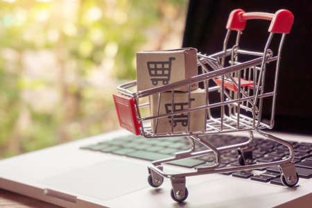 Shopping online concept - Parcel or Paper cartons with a shopping cart logo in a trolley on a laptop keyboard. Shopping service on The online web. offers home delivery.の写真素材