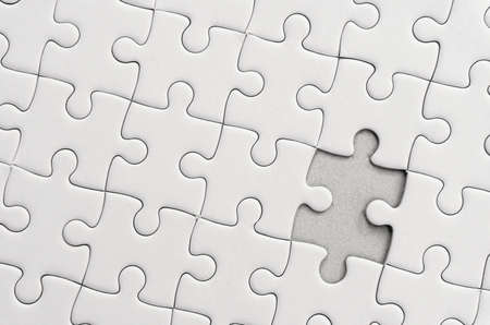 White jigsaw puzzle pattern background. placing last piece of jigsaw puzzleの写真素材