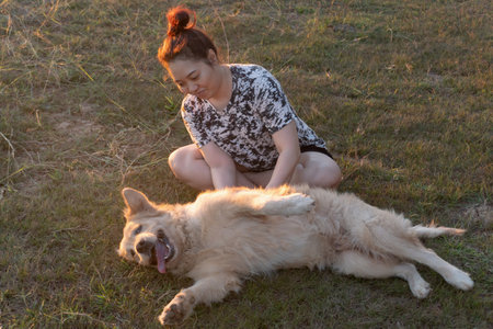 Woman and Golden retriever dog sitting near river or lakeの写真素材