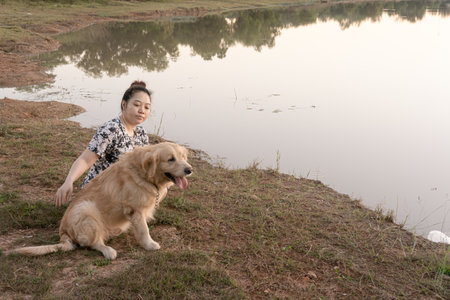 Woman and Golden retriever dog sitting near river or lakeの写真素材