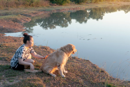 Woman and Golden retriever dog sitting near river or lakeの写真素材