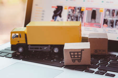 Logistics, and delivery service - Truck and paper cartons or parcel with a shopping cart logo on a laptop keyboard. Shopping service on The online web and offers home delivery.の写真素材