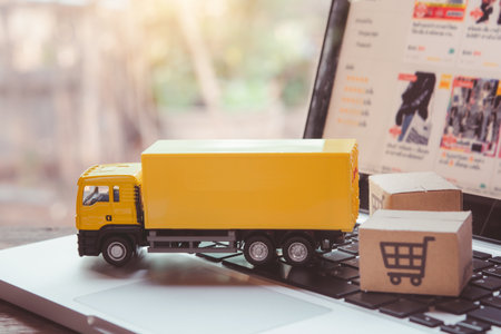 Logistics, and delivery service - Truck and paper cartons or parcel with a shopping cart logo on a laptop keyboard. Shopping service on The online web and offers home delivery.の写真素材