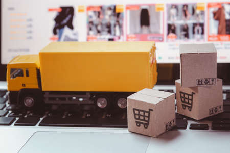 Logistics, and delivery service - Truck and paper cartons or parcel with a shopping cart logo on a laptop keyboard. Shopping service on The online web and offers home delivery.の写真素材