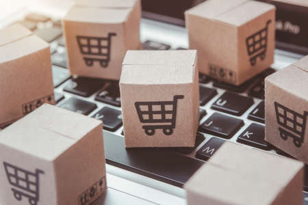Shopping online. Cardboard box with a shopping cart logo on laptop keyboard. Shopping service on The online web. offers home deliveryの写真素材