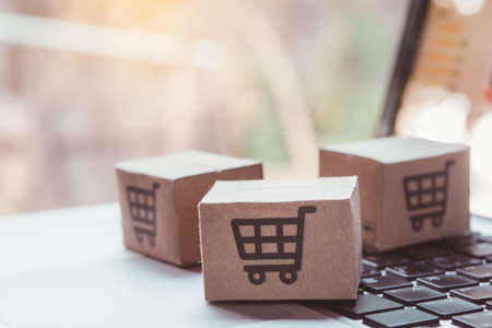 Shopping online. Cardboard box with a shopping cart logo on laptop keyboard. Shopping service on The online web. offers home deliveryの写真素材