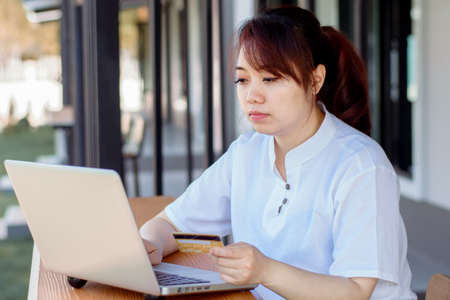 Online Payment . Asian woman holding credit card and using laptop with online shopping. Home shoppingの写真素材